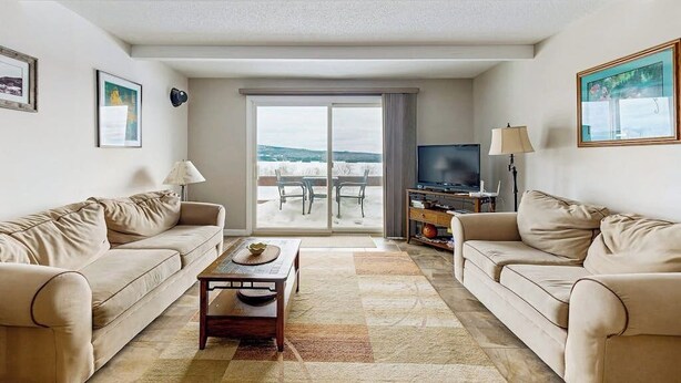 Un salon avec deux canapés, une table basse, un téléviseur et un balcon avec vue.