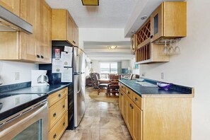 Eine Küche mit Holzschränken, einem Kühlschrank, einer Kaffeemaschine und einem Essbereich mit Stühlen und einem Tisch.