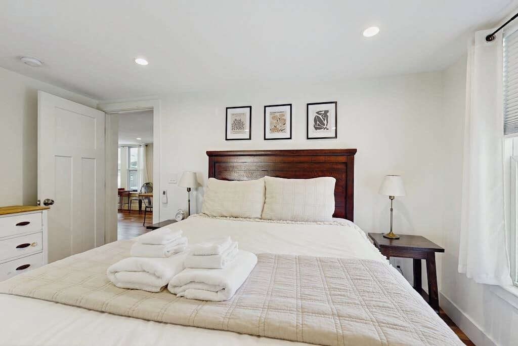 A neatly arranged bedroom with a bed, a bedside table, a lamp, and a door.
