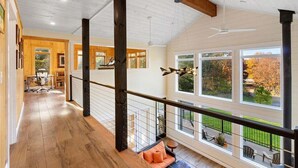 Un interior espacioso con techo alto, vigas de madera y ventanas grandes que ofrecen vistas al exterior.
