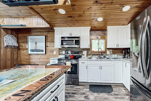A modern kitchen with white cabinets, stainless steel appliances, and a wooden ceiling. - Remodeled Cottage With AC, Private W/d, Full Kitchen, and High-speed Wifi (Boothbay Harbor)
