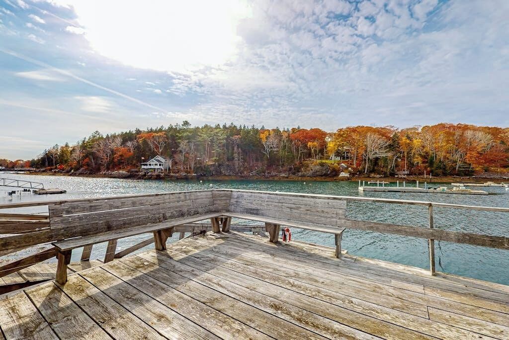 A wooden pier extending over a body of water with a forested shoreline in the background.