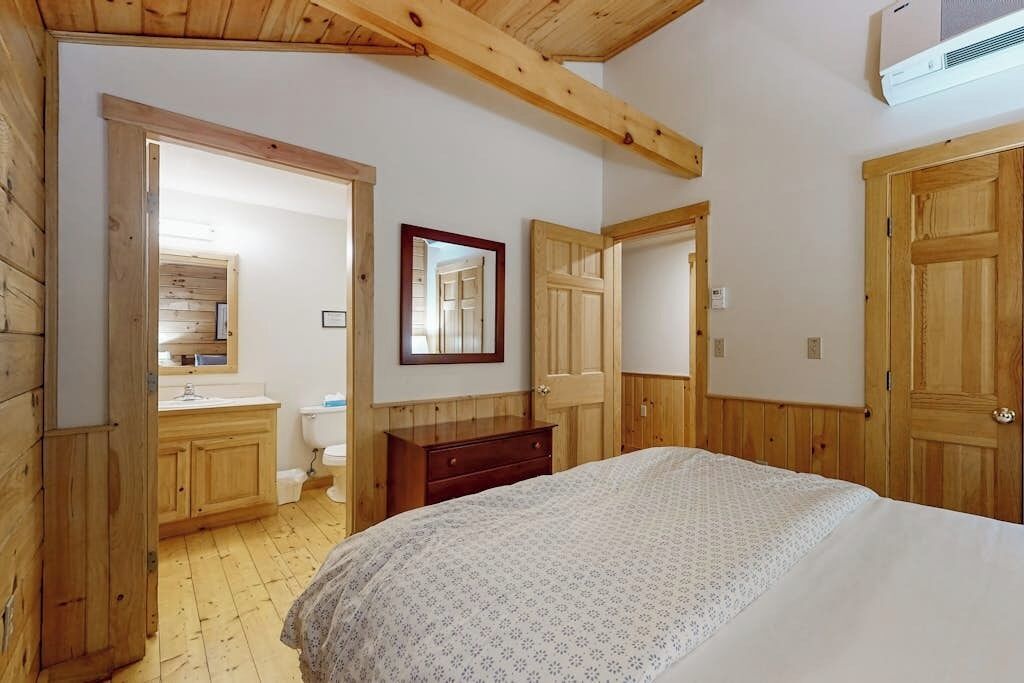 Un dormitorio con paredes de madera, una cama, un tocador y un espejo.