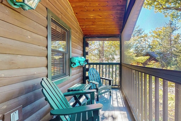 A wooden cabin with a porch, two Adirondack chairs, and a window with blinds. - Point Lookout South (Lincolnville)