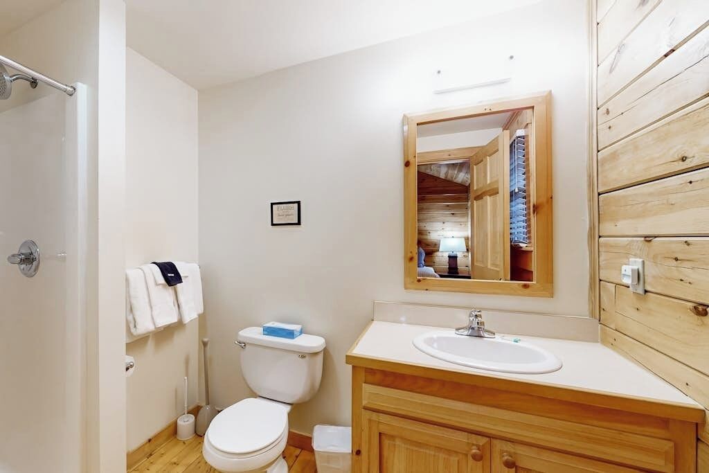 A compact bathroom with a toilet, sink, and wooden vanity.