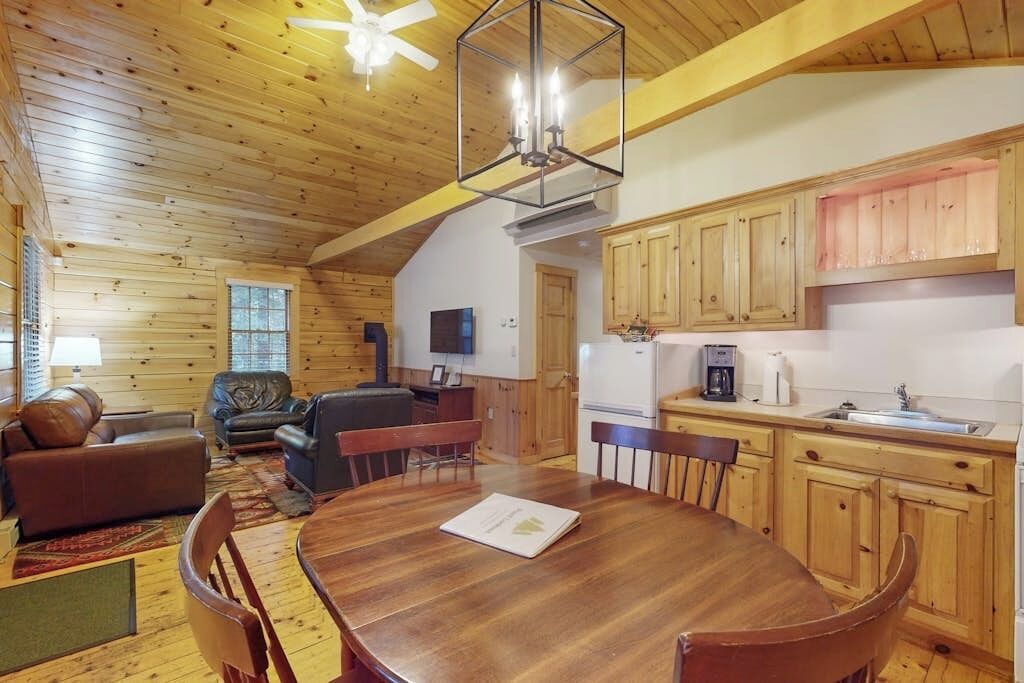 Un interior de madera con una mesa de comedor, sillas, un sofá y un televisor.