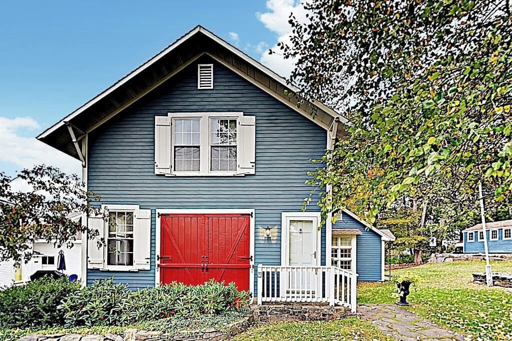 A blue house with a red door, white shutters, and a small porch.