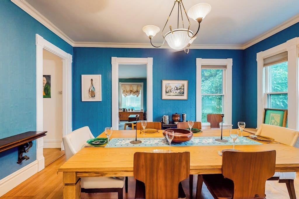 Uma sala de jantar com mesa de madeira, cadeiras e um candelabro.
