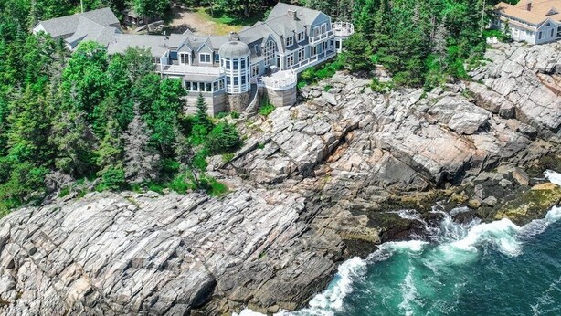 A large, multi-story house with a stone foundation, surrounded by dense forest and rocky coastline. - Spectacular Oceanfront Retreat With Amazing Views, Sunroom & Washer/dryer (Georgetown)