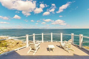 A wooden deck with white chairs and a table overlooking the ocean. - Spectacular Oceanfront Retreat With Amazing Views, Sunroom & Washer/dryer (Georgetown)