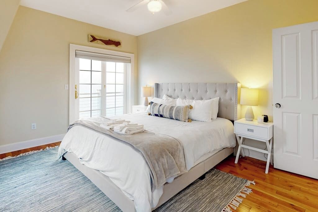 A bedroom with a bed, bedside tables, a door, and a window.