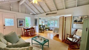 A cozy living room with a sofa, coffee table, and rocking chair. There are framed pictures on the walls and a door leading to another room. - Whispering Spruces; Cozy Studio With Queen Bed & W (South Thomaston)