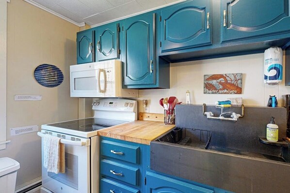 Une cuisine avec des armoires de couleur turquoise, un four blanc et un four à micro-ondes.