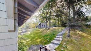 A house with a covered porch, a grassy yard, and a stone staircase leading to a door. - Charming Cottage: Deepwater Dock, Panoramic Linekin Bay Views, Near Village (Boothbay)