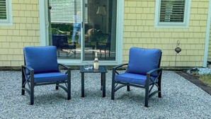 Due sedie blu con un tavolino tra loro, di fronte a una casa con una porta scorrevole in vetro.