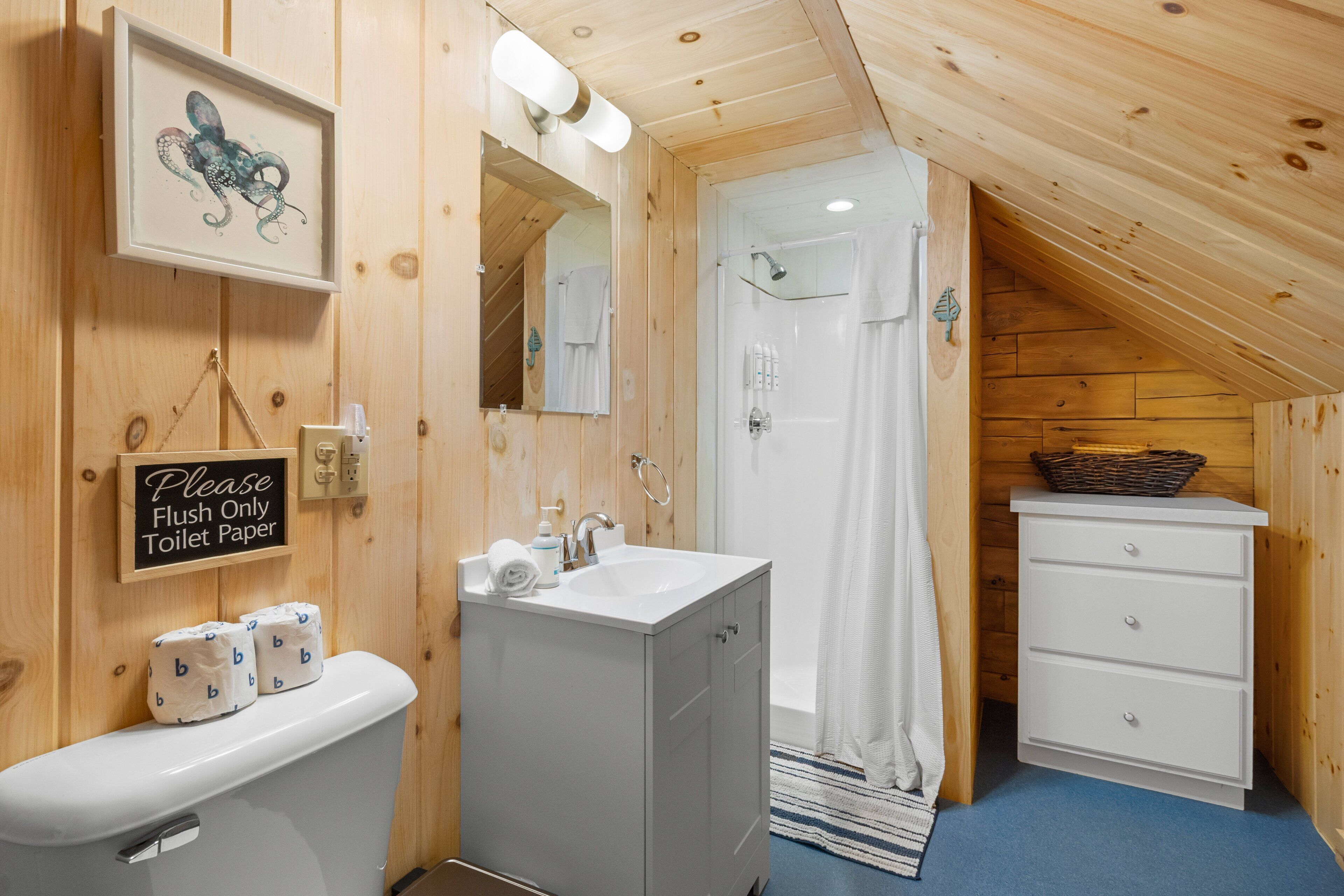 A wooden interior with a toilet, sink, and shower area.
