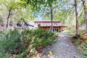 A two-story house with a balcony, surrounded by trees and a gravel path. - Waterfront Cabin w/ Outdoor Firepit, Dock, and Lake Views - Dogs Welcome (Greenville)