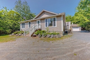 A single-story house with a front porch, a staircase leading to the entrance, and a garage. - Inviting Dog-friendly Home With Firepit & Ping-pong - Near Acadia National Park (Ellsworth)
