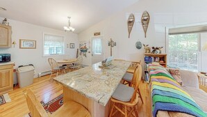 A kitchen with a granite countertop, wooden chairs, a dining table, and a bookshelf with decorative items. - Inviting Dog-friendly Home With Firepit & Ping-pong - Near Acadia National Park (Ellsworth)