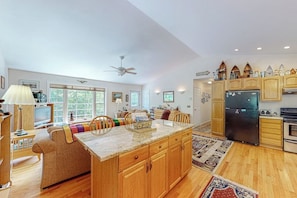 A spacious kitchen with wooden cabinets, a central island, and a large refrigerator. - Inviting Dog-friendly Home With Firepit & Ping-pong - Near Acadia National Park (Ellsworth)