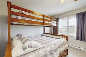 Quarto com beliche, janela, cortinas e ventilador de teto.