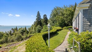 A coastal property with a well-maintained lawn, a gravel pathway, and a view of the sea. - Dog-friendly Oceanfront Home With Private Shorefront, two Fireplaces, & Firepit (Steuben)