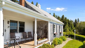 A house with a porch, outdoor seating, and a well-maintained garden. - Dog-friendly Oceanfront Home With Private Shorefront, two Fireplaces, & Firepit (Steuben)