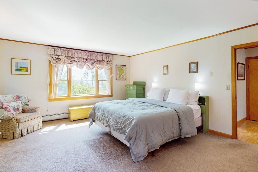 Een slaapkamer met een bed, een stoel, een raam en een deur.