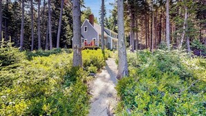 Ein Haus, umgeben von Wald, mit einem Kiesweg davor.
