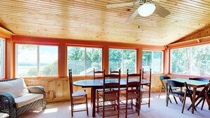 A room with a wooden ceiling, a dining table with chairs, a sofa, and large windows with a view. - Dog-friendly, Bay View Home With Wifi & Laundry - Close to Baxter State Forest (Bowdoinham)
