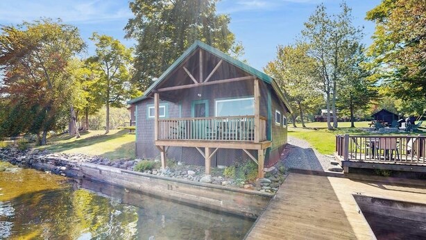 A cabin with a deck, a pond, and a grassy area with trees. - Dog-friendly Lakefront Cabin With Private Dock, Epic Views of Lake & Mt Kineo (Rockwood)