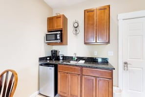 A compact kitchen with wooden cabinets, a microwave, a coffee maker, and a dishwasher. - Lovely Downtown Northeast Harbor Suite Near the Water and Near Acadia (Northeast Harbor)