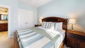 A bedroom with a bed, nightstands, a wooden headboard, a ceiling fan, and a door leading to a bathroom. - Lovely Downtown Northeast Harbor Suite Near the Water and Near Acadia (Northeast Harbor)