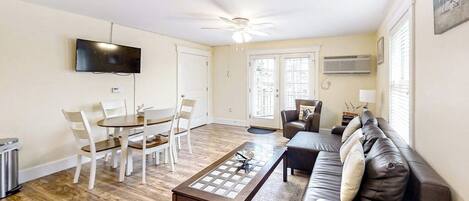 Un salon comprenant une table à manger, des chaises, un canapé, un téléviseur et un ventilateur de plafond.