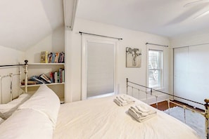 Ein Schlafzimmer mit einem Bett, einem Bücherregal, einem Fenster und einer Tür.