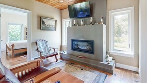 A living room with a fireplace, a television mounted on the wall, and a large window. - Dog-friendly Home With High-speed Wifi, Washer/dryer, & Private Dock (Harpswell)