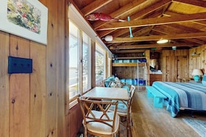 A wooden cabin interior with a bed, seating area, and a table. - Beachfront Delight With Detached Guesthouse, Private Beach Access, Dog-friendly (Southport)