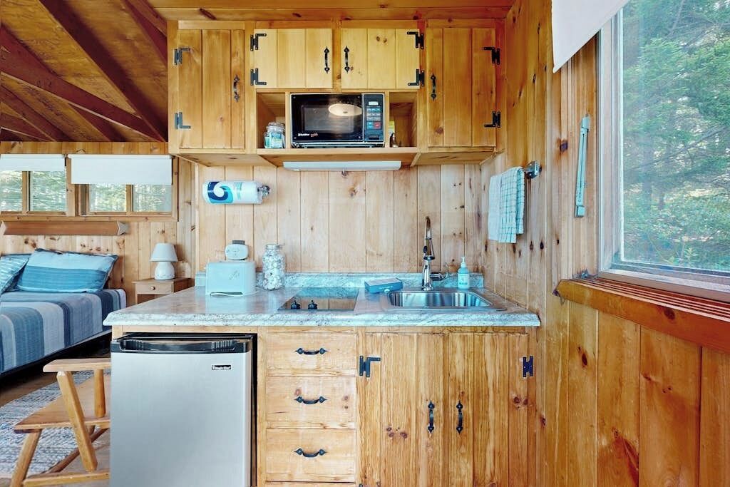 A compact kitchen with wooden cabinets, a microwave, and a sink.