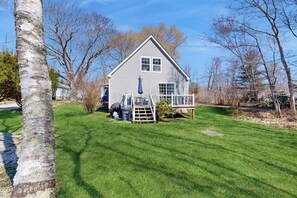 Ein eingeschossiges Haus mit Veranda, kleiner Terrasse und gepflegtem Rasen.