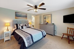 A bedroom with a bed, a ceiling fan, a dresser, a chair, a TV, and a painting on the wall. - Serene Home With a Deck, Grill, Firepit, Board Games, Washer/dryer, & mtn Views (Ellsworth)