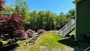 A residential property with a well-maintained garden, a stone pathway, and a staircase leading to a green building. - Hillhouse, Tastefully Decorated Maine Home (Rockport)
