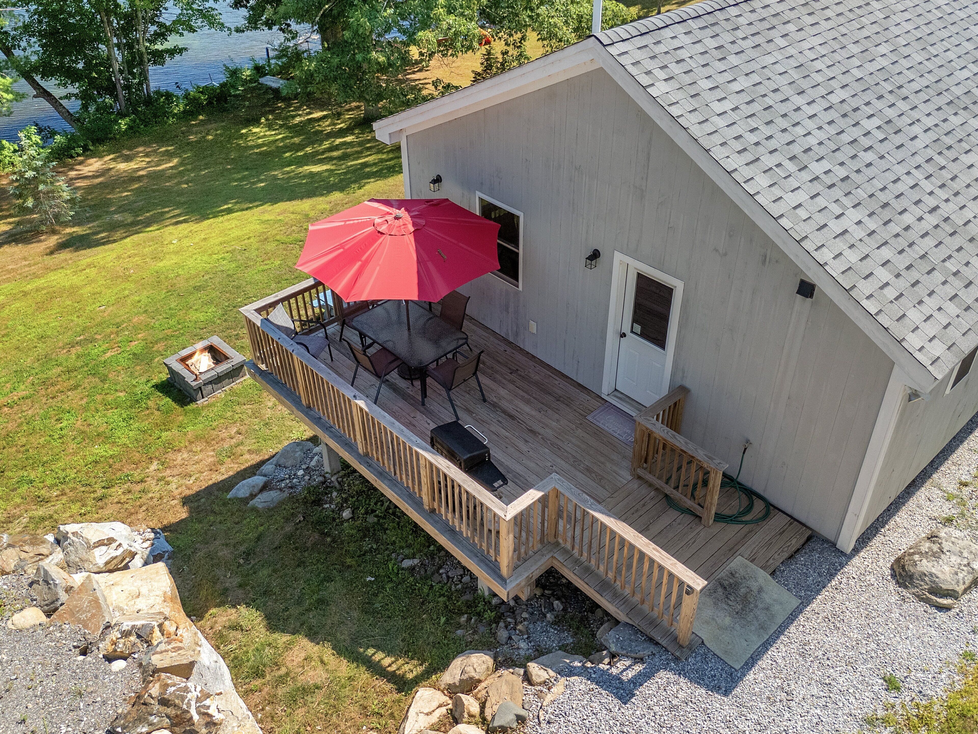Ein Haus mit einer Terrasse, einer Feuerstelle und einem roten Sonnenschirm.