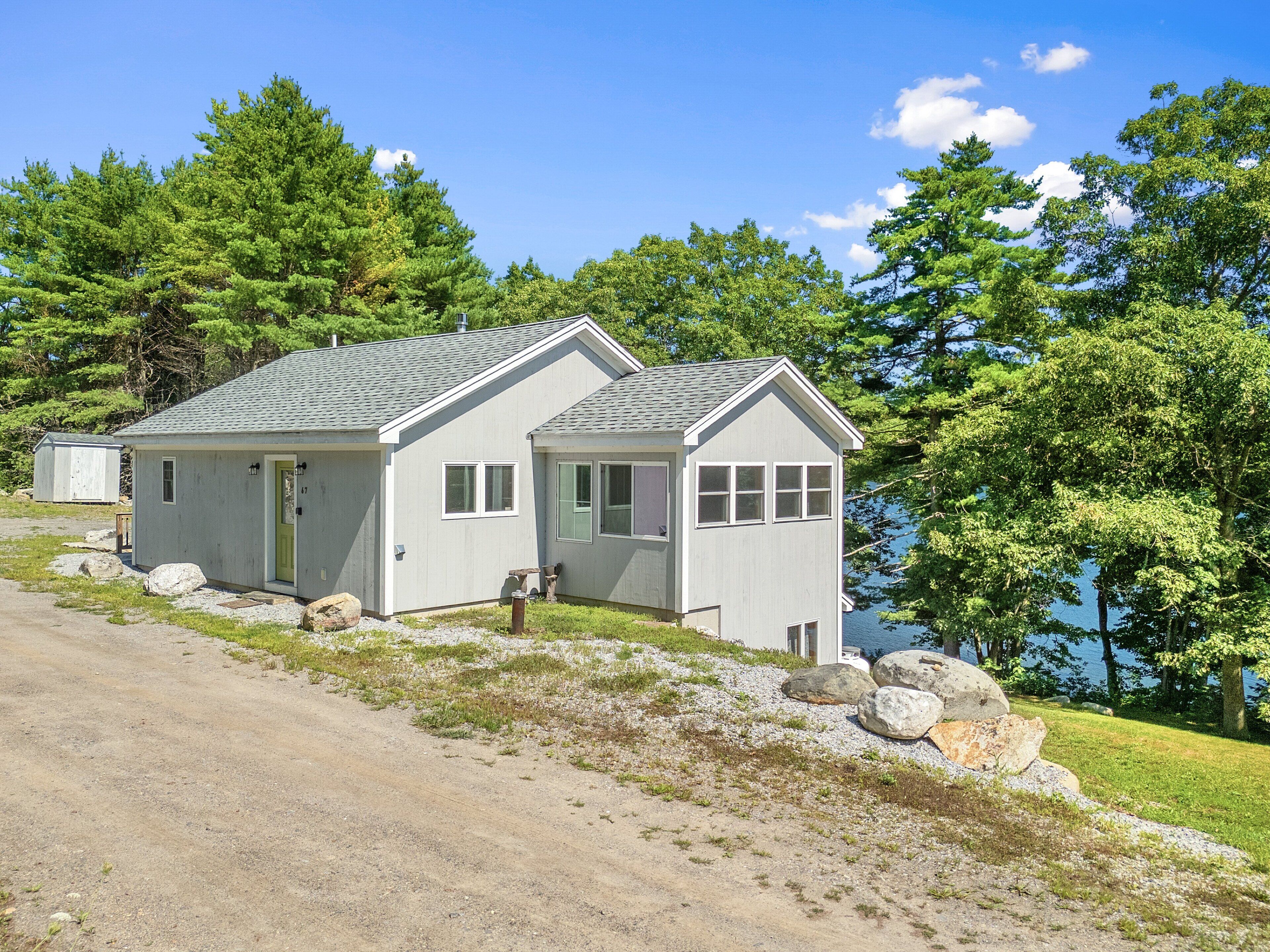 A single-story house with a gabled roof, a front porch, and a view of a lake.