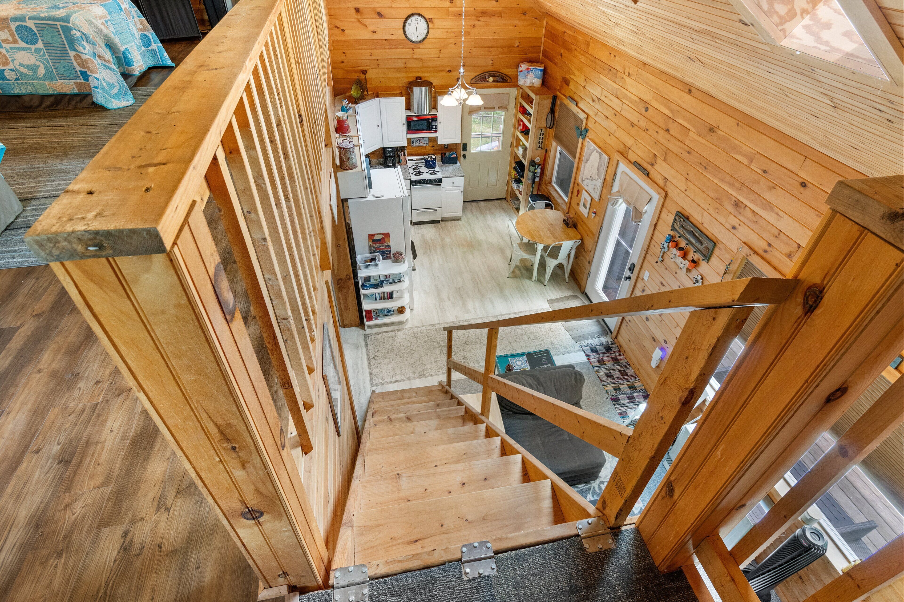 Interior de una cabaña de madera con cocina, comedor y escalera.