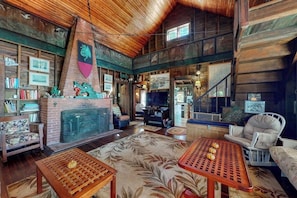 A rustic interior with a fireplace, wooden walls, and a high ceiling. - Spacious Waterfront Estate & Cabins W/ Porch, Fireplace, Kayaks & Free Wifi (Brunswick)