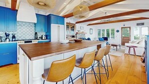 Een moderne keuken met blauwe kastjes, een houten eiland en hangende rieten lampen.