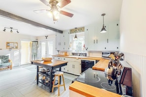 A modern kitchen with white cabinets, a central island, a stove, and a ceiling fan. - Renovated 19th-century Farmhouse w/ 270 Feet of Waterfront & Sunset Views (Penobscot)
