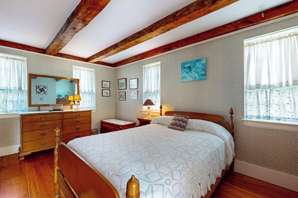 Ein Schlafzimmer mit einem hölzernen Bett, einem Schminktisch, einem Spiegel und gerahmten Bildern an der Wand.