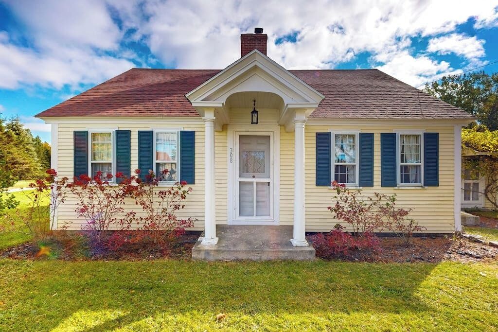 A two-story house with a front porch, a central entrance, and a chimney.