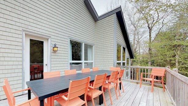 A deck with a table and chairs, a door, and windows. - Home With Deck, Great Location in the Heart of Acadia National Park (Mount Desert)